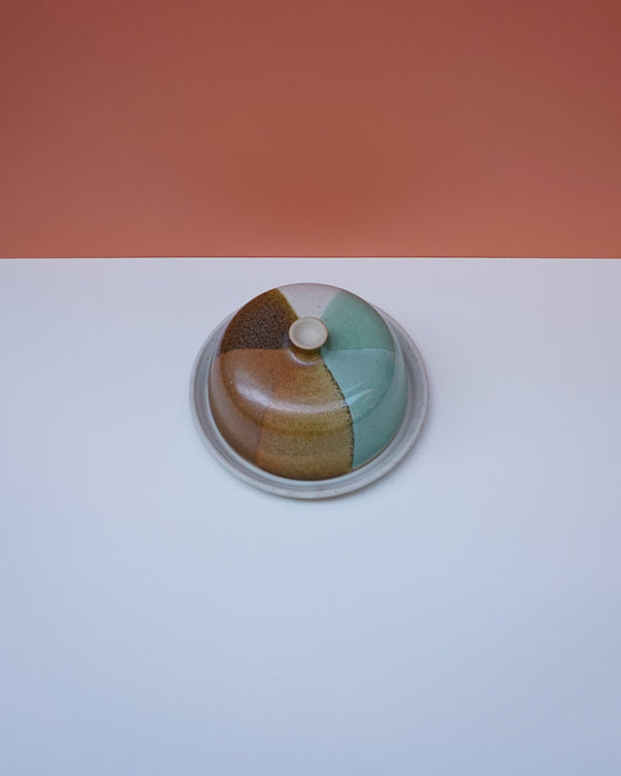 Ceramic pot with multicolored glaze on a white surface with an orange background. Liz Vidal Ceramics | Shop Fodder
