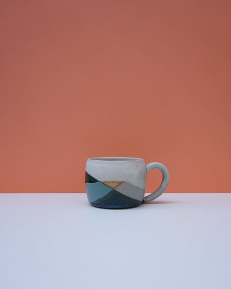 Ceramic mug with geometric design on a peach and white background. Liz Vidal Ceramics | Shop Fodder