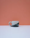 Ceramic mug with a black and white design on a peach and white background. Liz Vidal Ceramics | Shop Fodder