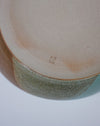 Close-up of a ceramic bowl with a speckled pattern on a white background. Liz Vidal Makers Mark. Fodder