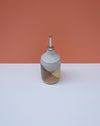 Ceramic bottle with a striped design on a white surface and orange background. Liz Vidal Ceramics | Shop Fodder