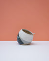 Ceramic pot with geometric design on a white surface and peach background. Liz Vidal Ceramics | Shop Fodder