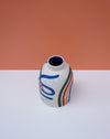 Ceramic vase with colorful abstract design on a white surface and orange background. Sophie Alda | Handmade Ceramics | Shop Fodder