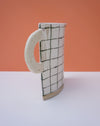 Ceramic mug with grid pattern on an orange and white background. Sophie Alda | Handmade Ceramics | Shop Fodder