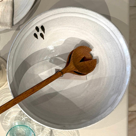 White ceramic bowl with a wooden spoon on a light background by lily pearmain. 