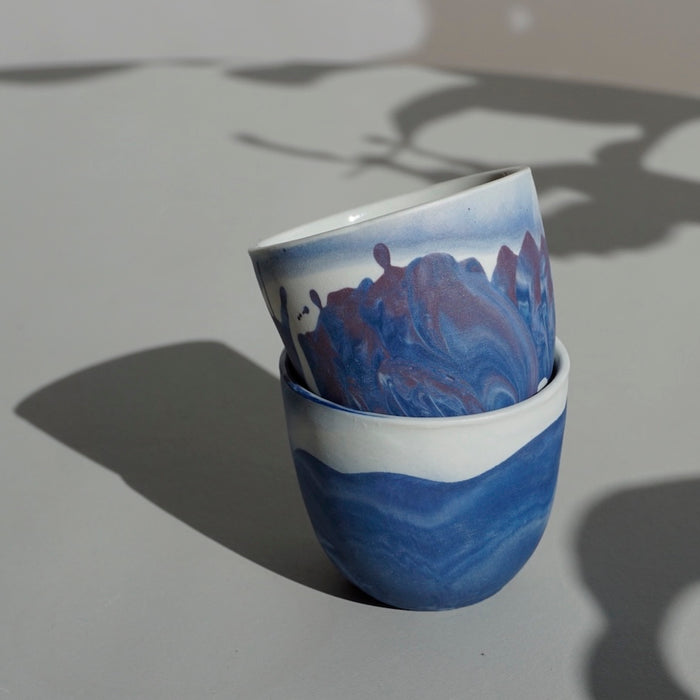 close up of two blue and purple handmade coffee cups. 