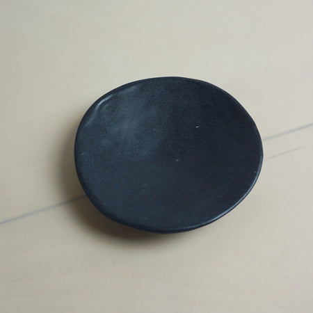 Black circular object on a light gray surface. Diddy Bowl | Jode Pankhurst | Shop Fodder