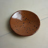 Brown ceramic plate with black speckles on a light gray surface. Diddy Bowl | Jode Pankhurst | Shop Fodder