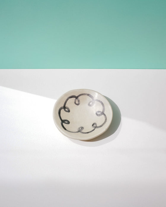 Round ceramic dish with decorative black pattern on a light green and white background. Diddy Bowl | Jode Pankhurst | Shop Fodder