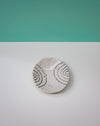 Round ceramic coaster with black patterns on a white surface with a teal background. Diddy Bowl | Jode Pankhurst | Shop Fodder