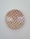 Round ceramic plate with grid pattern on a light gray background. Diddy Bowl | Jode Pankhurst | Shop Fodder