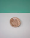 Round wooden coaster with striped pattern on a white surface with teal background. Diddy Bowl | Jode Pankhurst | Shop Fodder