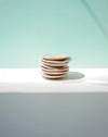 Stack of ceramic plates on a white surface with a light green background. Diddy Bowl | Jode Pankhurst | Shop Fodder