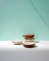 Stack of ceramic plates on a light surface with a light blue background. Diddy Bowl | Jode Pankhurst | Shop Fodder