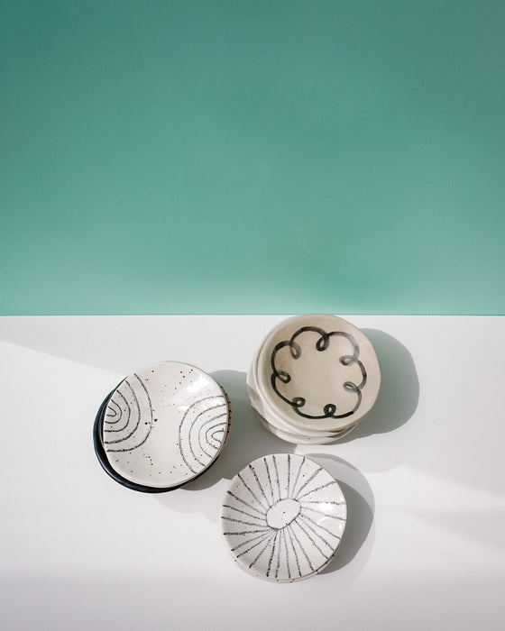 Three ceramic dishes with abstract patterns on a white surface and teal background. Diddy Bowl | Jode Pankhurst | Shop Fodder