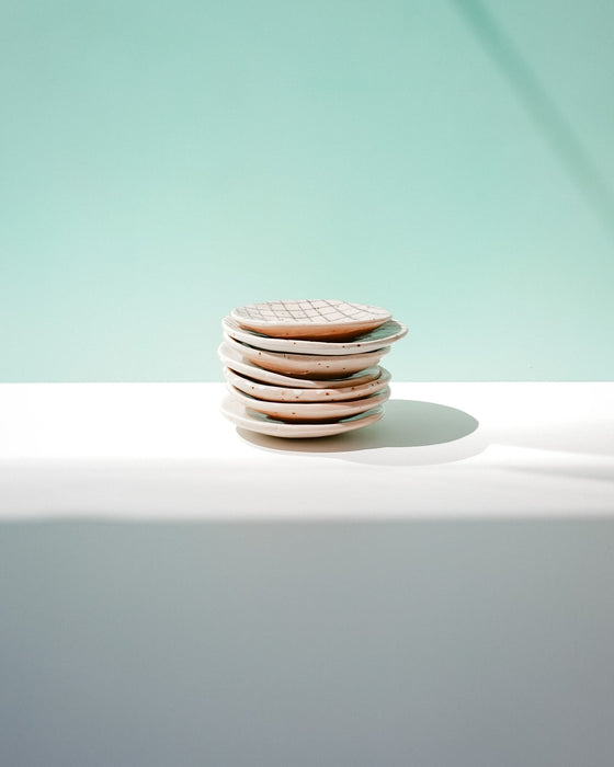Stack of ceramic plates on a white surface with a light green background. Diddy Bowl | Jode Pankhurst | Shop Fodder