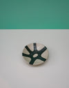 Ceramic plate with green abstract design on a white surface with teal background. Diddy Bowl | Jode Pankhurst | Shop Fodder