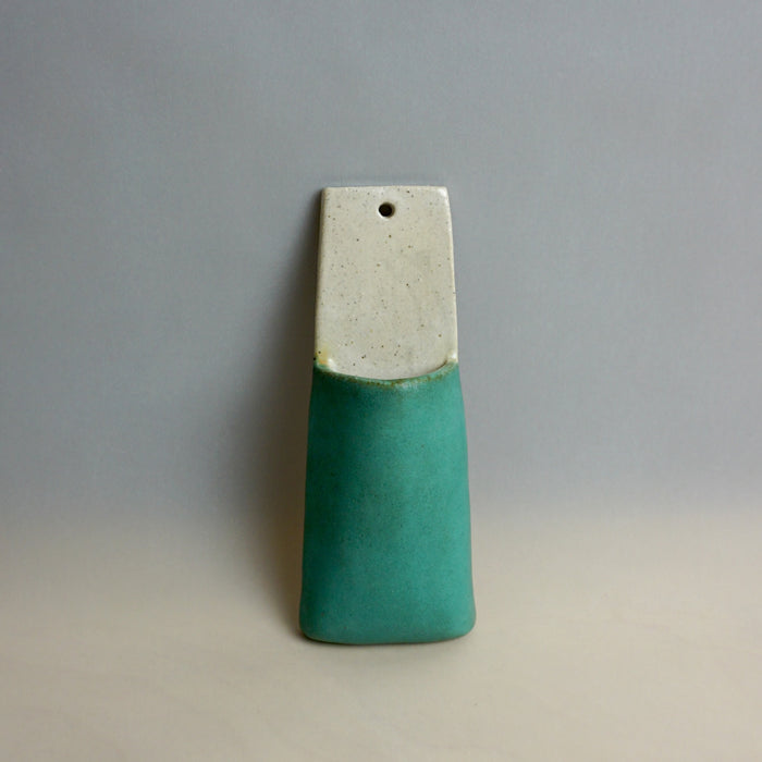 Ceramic pendant with a white top and green bottom on a gray background. Pocket Wall | Jode Pankhurst | Shop Fodder