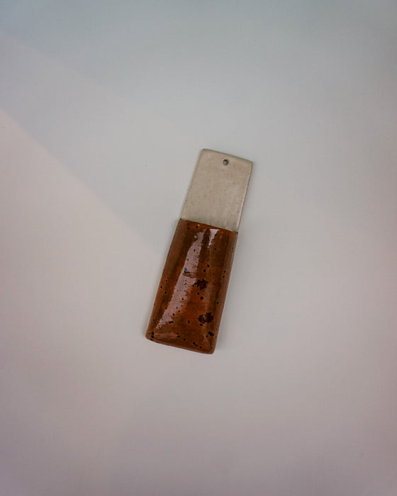 Rectangular object with a metallic top and brown bottom on a light gray background | Jode Pankhurst