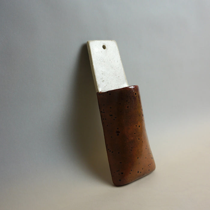 Brown ceramic vase with a metallic blade on a gradient gray background. Pocket Wall | Jode Pankhurst | Shop Fodder
