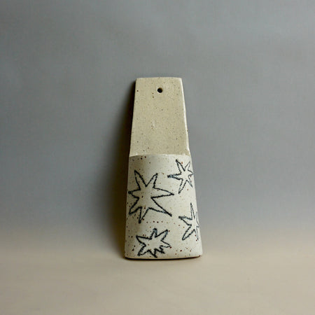 Cylindrical ceramic object with star patterns on a grey background. Pocket Wall | Jode Pankhurst | Shop Fodder