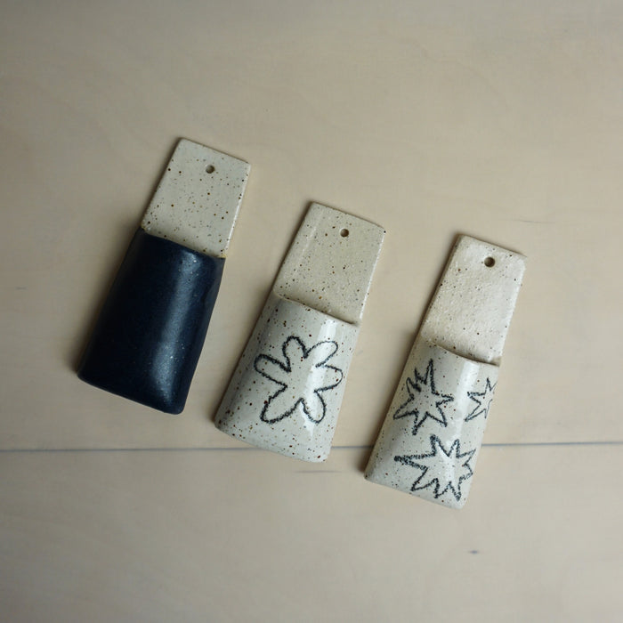 Four ceramic pendants with star designs on a beige surface. Pocket Wall | Jode Pankhurst | Shop Fodder