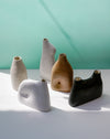 Five ceramic vases in different colors on a light surface with a teal background | Jode Pankhurst