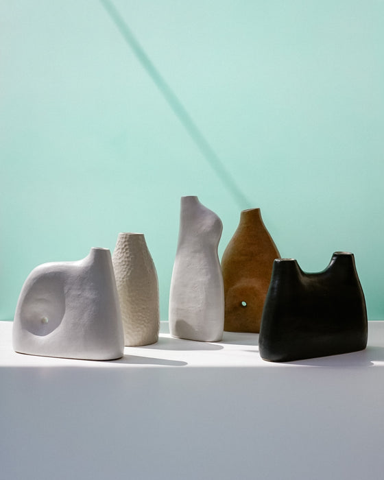 Five ceramic vases of different shapes and colors on a light surface with a light green background | Jode Pankhurst