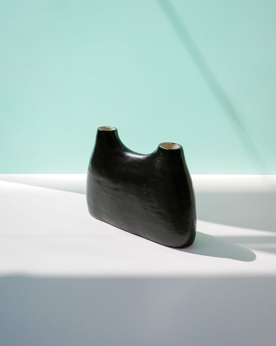 Black ceramic vase on a white surface with a light blue background | Jode Pankhurst