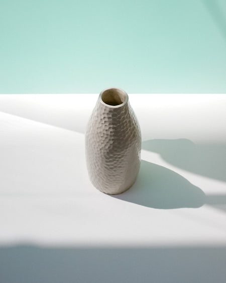 Textured ceramic vase on a light surface with a soft green background | Jode Pankhurst