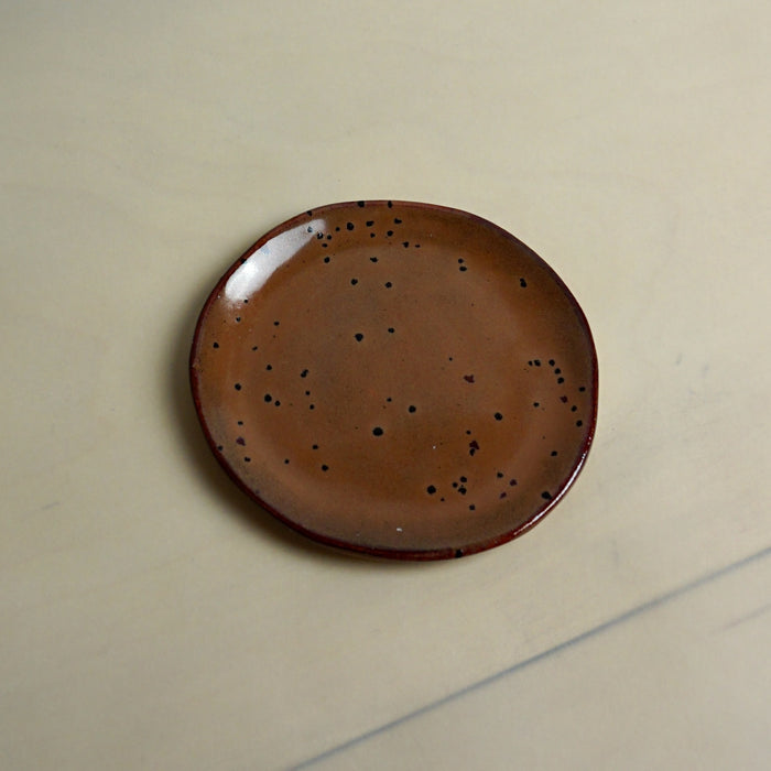 Brown ceramic plate with speckled pattern on a beige background. Trinket Dish | Jode Pankhurst | Shop Fodder