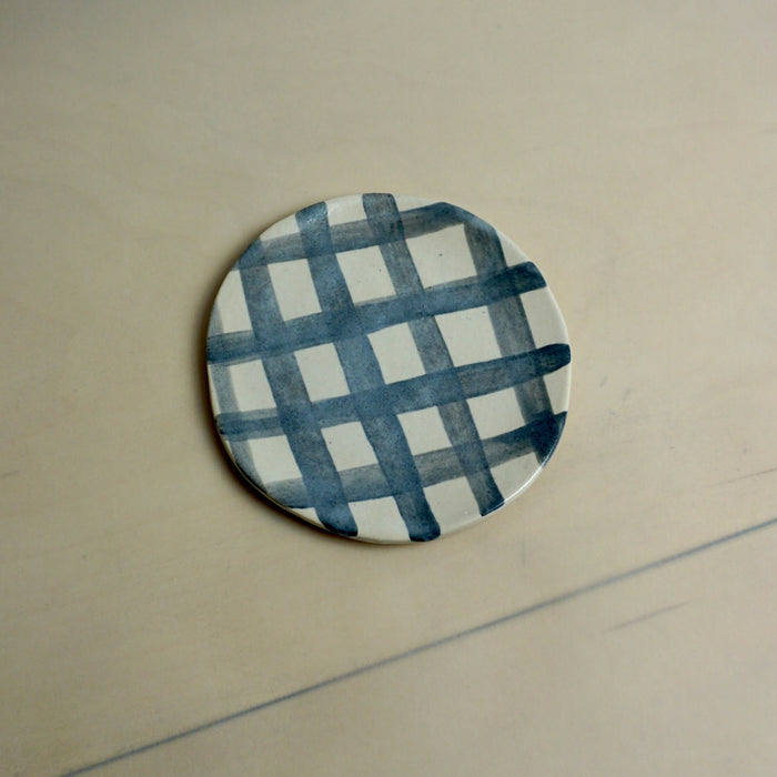 Round ceramic coaster with blue and white checkered pattern on a beige surface. Trinket Dish | Jode Pankhurst | Shop Fodder