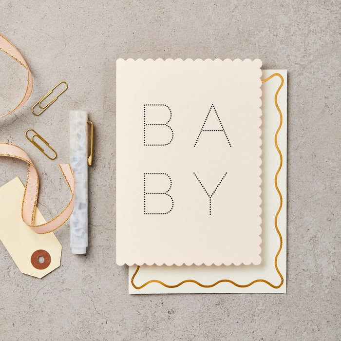 pink card with scalloped edges that says BABY.