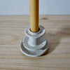 Close up detail of white handmade candlestick holder by Mae Ceramics with a Beeswax candle. 