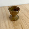 Brown ceramic egg cup on a wooden surface. Lily Pearmain Ceramics | Shop Fodder
