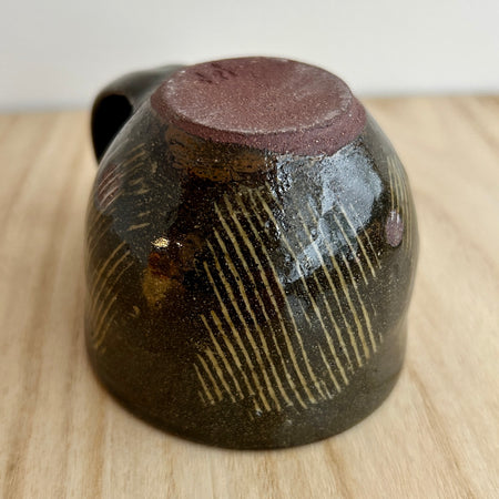Ceramic cup with brown glaze and textured surface on a wooden surface. Lily Pearmain Ceramics | Shop Fodder