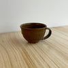 Brown ceramic mug on a light wooden surface with a white background. Lily Pearmain Ceramics | Shop Fodder