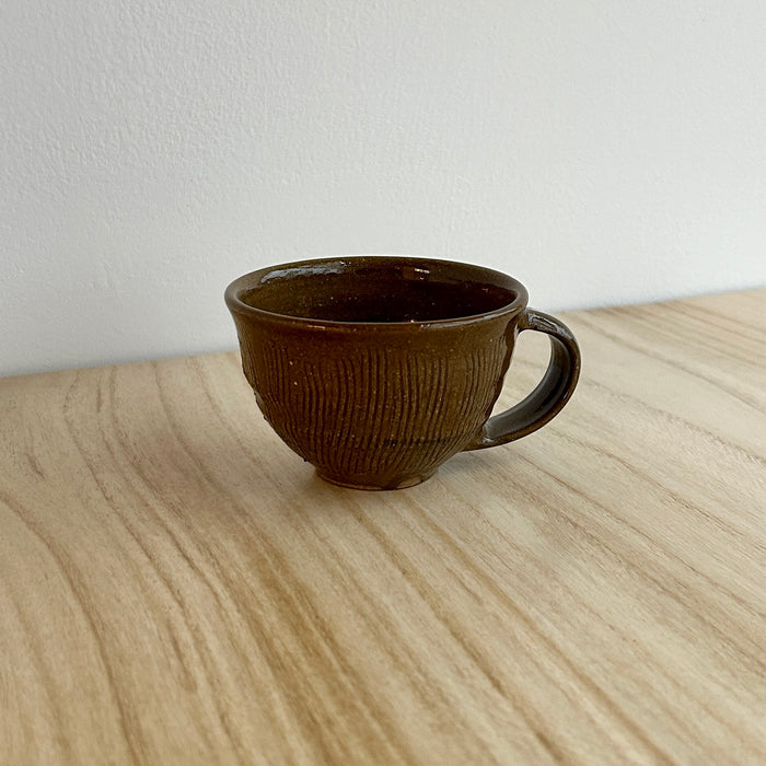 Brown ceramic mug on a light wooden surface with a white background. Lily Pearmain Ceramics | Shop Fodder