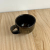 Black ceramic mug on a wooden surface. Lily Pearmain Ceramics | Shop Fodder