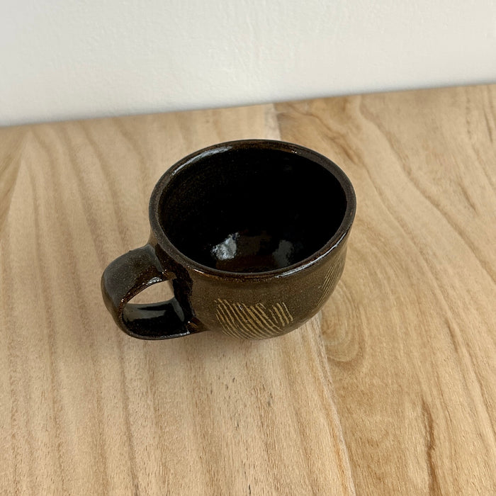 Black ceramic mug on a wooden surface. Lily Pearmain Ceramics | Shop Fodder