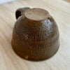 Brown ceramic cup with textured surface on a light wooden surface. Lily Pearmain Ceramics | Shop Fodder