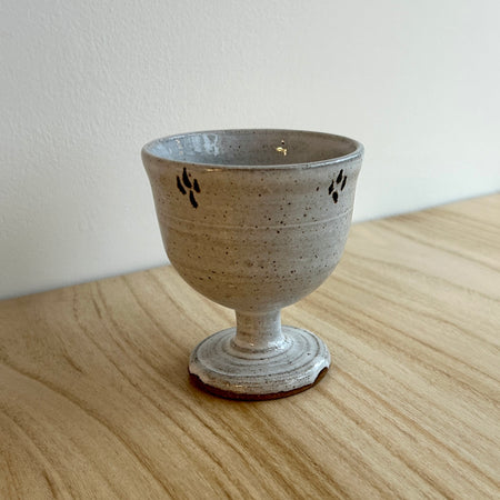 Ceramic goblet with speckled glaze on a wooden surface. Lily Pearmain Ceramics | Shop Fodder