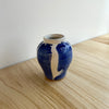 Blue and white ceramic vase on a wooden surface with a white wall background. Mae Ceramics | Shop Fodder