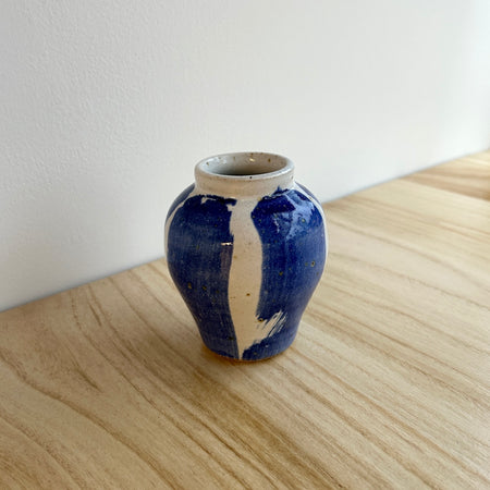 Blue and white ceramic vase on a wooden surface with a white wall background. Mae Ceramics | Shop Fodder