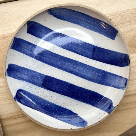 Ceramic plate with blue and white stripes on a wooden surface. Mae Ceramics | Shop Fodder
