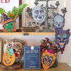 Decorative shelf with Halloween-themed masks and candles. Masks | East End Press | Shop Fodder