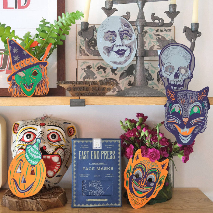 Decorative shelf with Halloween-themed masks and candles. Masks | East End Press | Shop Fodder