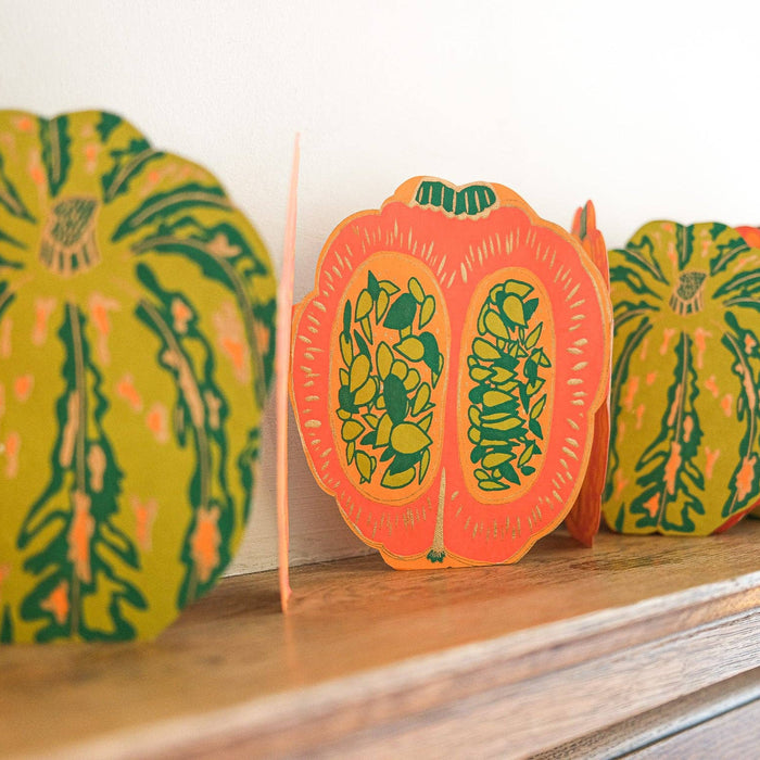 Decorative paper pumpkins with green leaf patterns on a wooden Mantelpiece. Pumpkin Handprinted Garland | East End Press | Shop Fodder