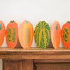 Decorative paper pumpkins on a wooden surface against a white wall. Pumpkin Handprinted Garland | East End Press | Shop Fodder