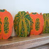Decorative paper pumpkins with intricate designs on a wooden surface. Pumpkin Handprinted Garland | East End Press | Shop Fodder
